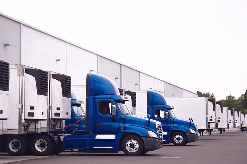 Refrigerated trucks with blue cabs at a loading dock