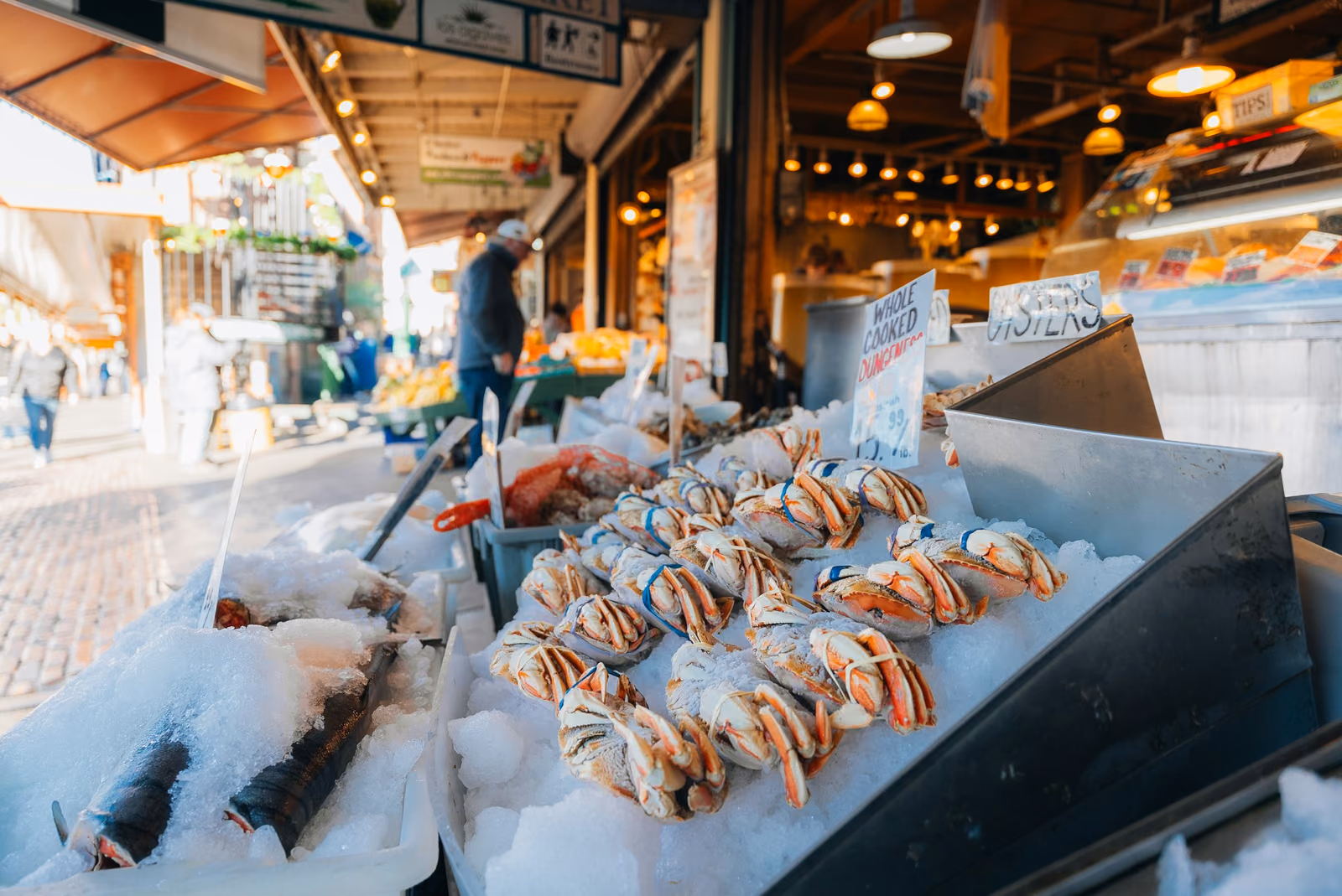 Whole crabs, prawns and fish laid out on ice at a market counter